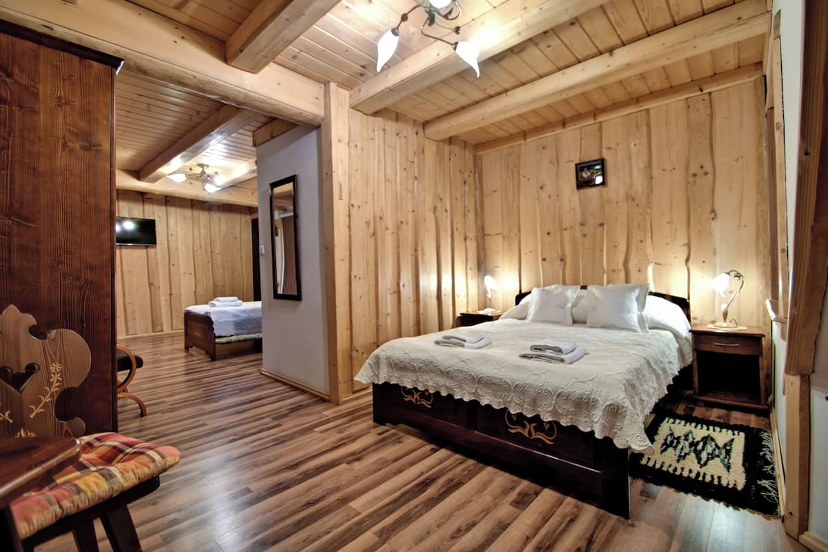 Una habitación con paneles de madera, una cama, una silla, una mesita de noche y un televisor.