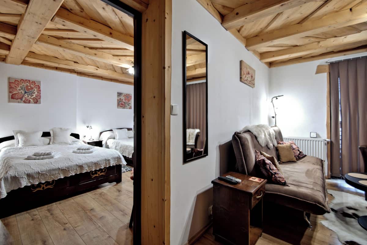 Un dormitorio con techo de madera, una cama con cubrecama blanco, un sofá marrón y un espejo en la pared.