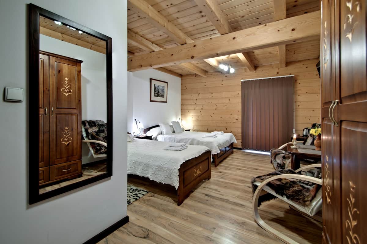 Una habitación con paneles de madera, dos camas, un espejo, un armario y una silla.