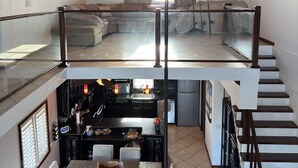 Un loft espacioso con techo alto, comedor, cocina y escalera.