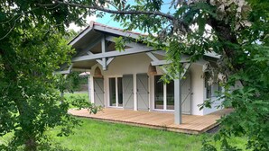 Ein Haus mit Holzterrasse, großen Schiebeglastüren und einem überdachten Veranda-Bereich.