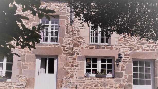 A stone building with two white doors, a window with a flower box, and a metal chair outside. - Charming gîte in a hamlet near the Rance, between Dinard, Dinan and St Malo (Le Minihic-sur-Rance)