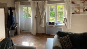 A room with a white door, a window with curtains, a radiator, and a tiled floor. - Charming gîte in a hamlet near the Rance, between Dinard, Dinan and St Malo (Le Minihic-sur-Rance)