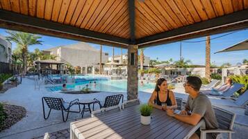 An outdoor pool area with lounge chairs and a covered seating area.