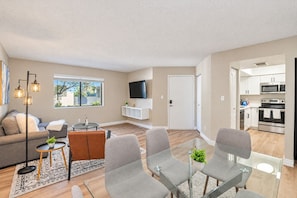 A modern living room with a sofa, armchairs, a coffee table, and a TV.