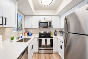 A modern kitchen with stainless steel appliances, white cabinetry, and a built-in oven. - Sunny Scottsdale Retreat with  Pool, Gym & Parking (Scottsdale)