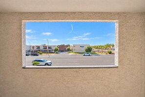 A window view of a street with buildings, cars, and a clear sky.