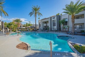A swimming pool with a curved design, surrounded by palm trees and a building with a sign that reads 'NO LEASES'. - Sunny Scottsdale Retreat with  Pool, Gym & Parking (Scottsdale)