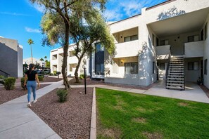 Un bâtiment moderne doté d’une galerie couverte, d’un espace extérieur aménagé pour s’asseoir et d’une pelouse bien entretenue.
