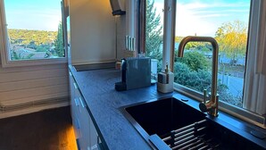 Une cuisine moderne dotée d’une grande fenêtre, d’un évier encastré et d’une cuisinière compacte.