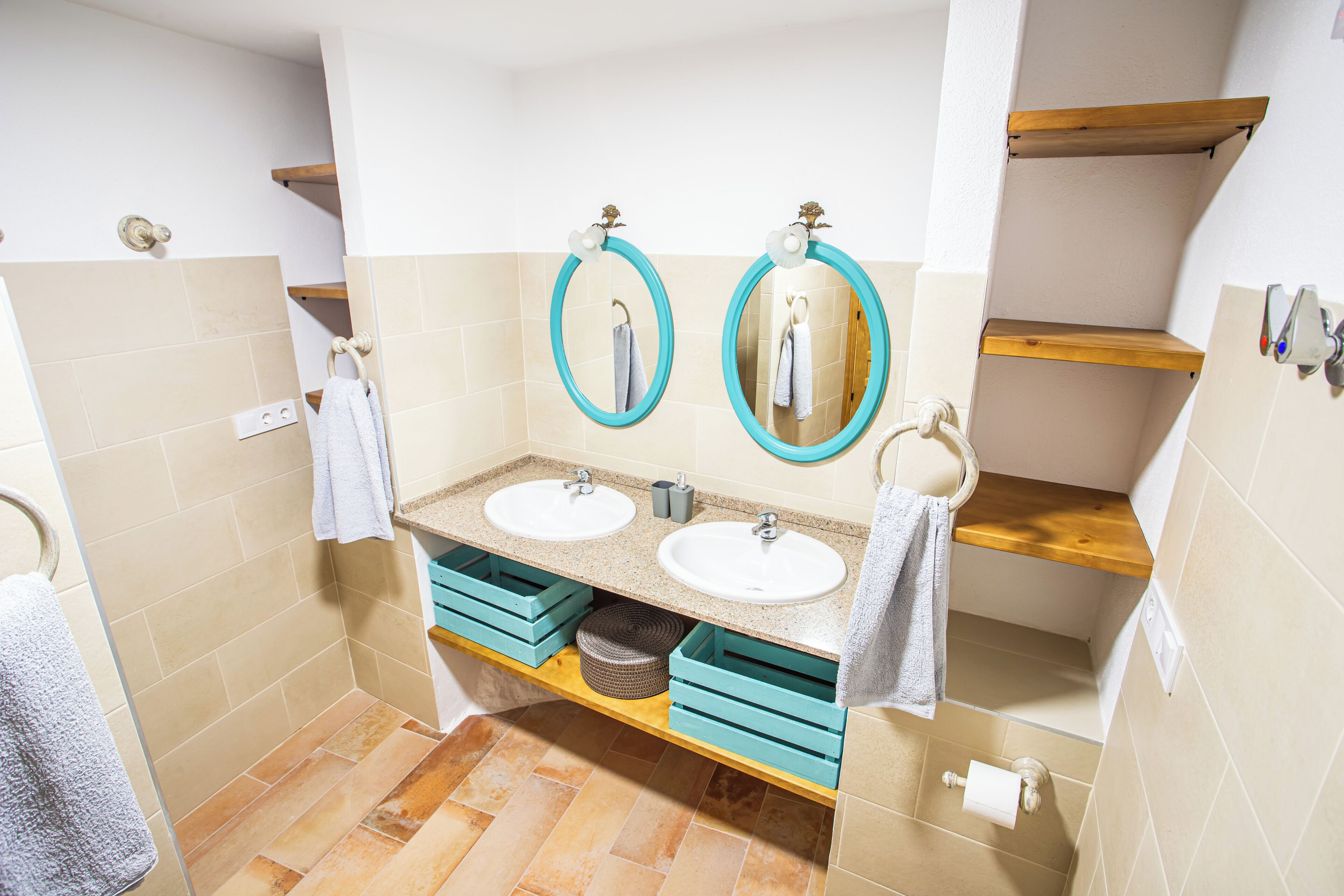 A bathroom with two sinks, two mirrors, and wooden shelves.