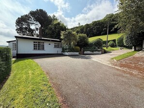 A white building with a gravel driveway, surrounded by greenery and hills. - Benarth Lodge a charming unique hideaway in Conwy (iverside Business Park)