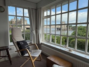 A room with a large window, a chair with a cushion, a small table, and a radiator. - Benarth Lodge a charming unique hideaway in Conwy (iverside Business Park)