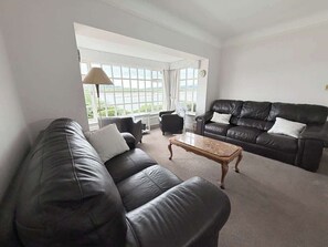 Ein Wohnzimmer mit einem schwarzen Ledersofa, einem Holztisch und einer schwarzen Lederecke.