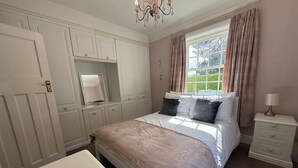 A bedroom with a bed, a nightstand, a dresser, and a window with curtains. - Benarth Lodge a charming unique hideaway in Conwy (iverside Business Park)