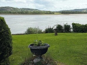 A garden with a large planter in the foreground and a river in the background. - Benarth Lodge a charming unique hideaway in Conwy (iverside Business Park)