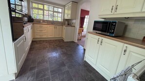 A kitchen with white cabinets, a microwave, and a tiled floor. - Benarth Lodge a charming unique hideaway in Conwy (iverside Business Park)