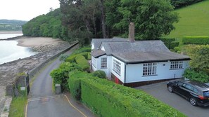 A coastal house with a paved driveway, a parked car, and a view of the sea. - Benarth Lodge a charming unique hideaway in Conwy (iverside Business Park)