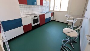 A compact kitchen with a gas stove, oven, and a small dining area with a metal table and two chairs.