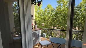 Ein Balkon mit Tisch, Stühlen, einem Blumentopf und Blick auf Bäume.