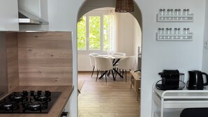Eine moderne Küche mit Kochinsel, einem Essbereich inklusive Tisch und Stühlen sowie einer Kaffeestation.