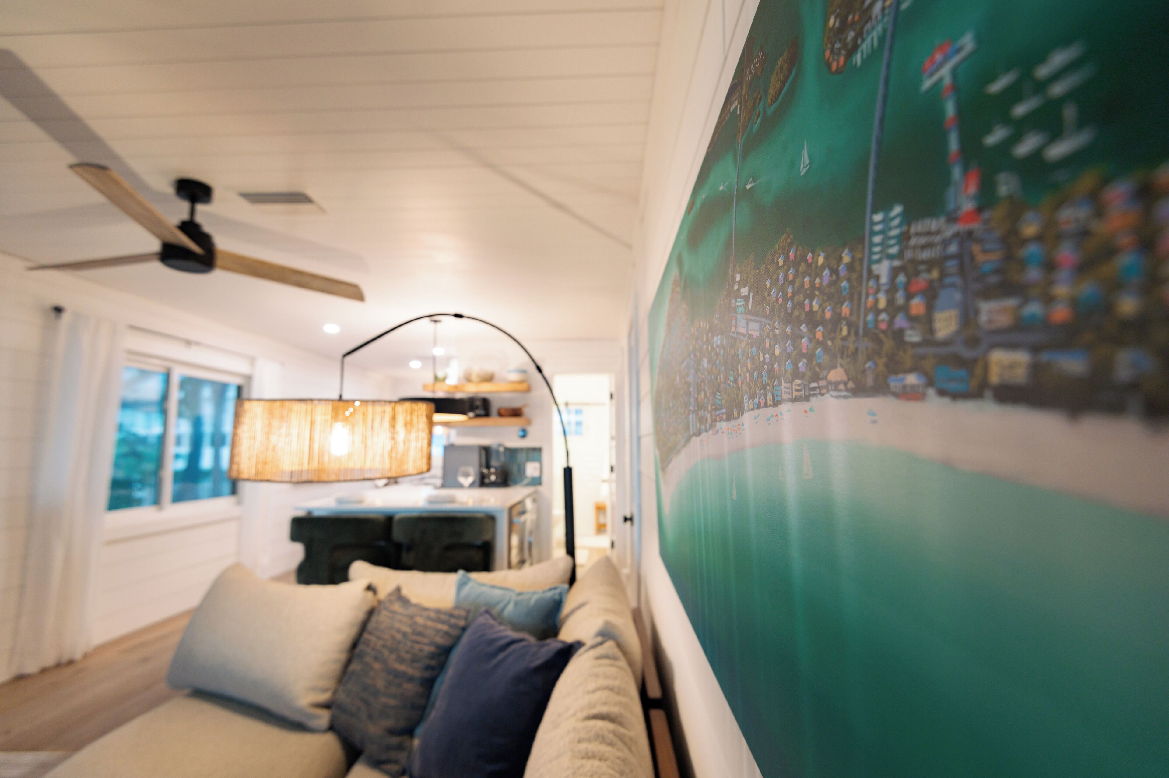 A cozy living room with a sofa, a ceiling fan, and a wall-mounted lamp.