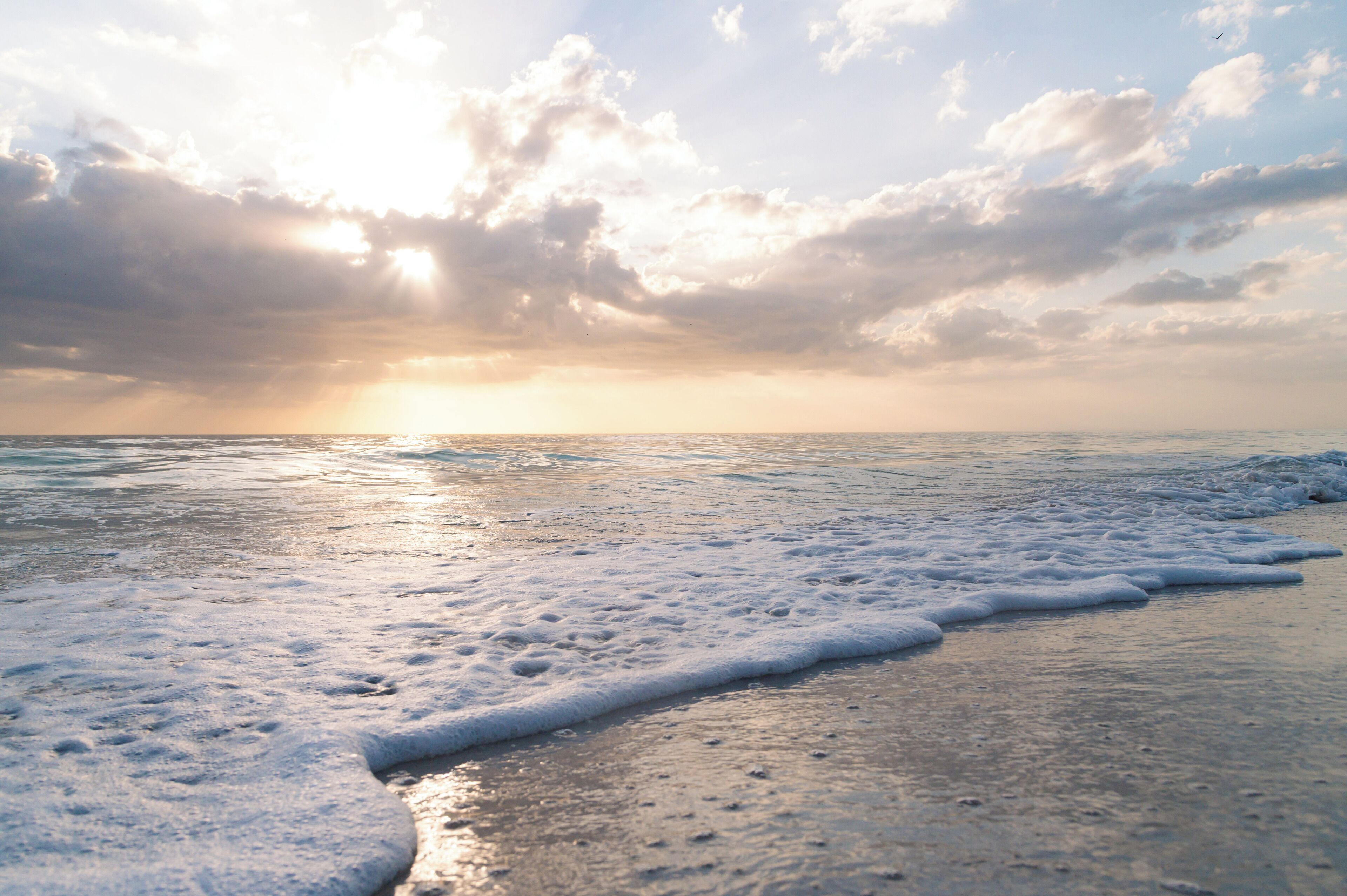 A beach with waves and a sunset.