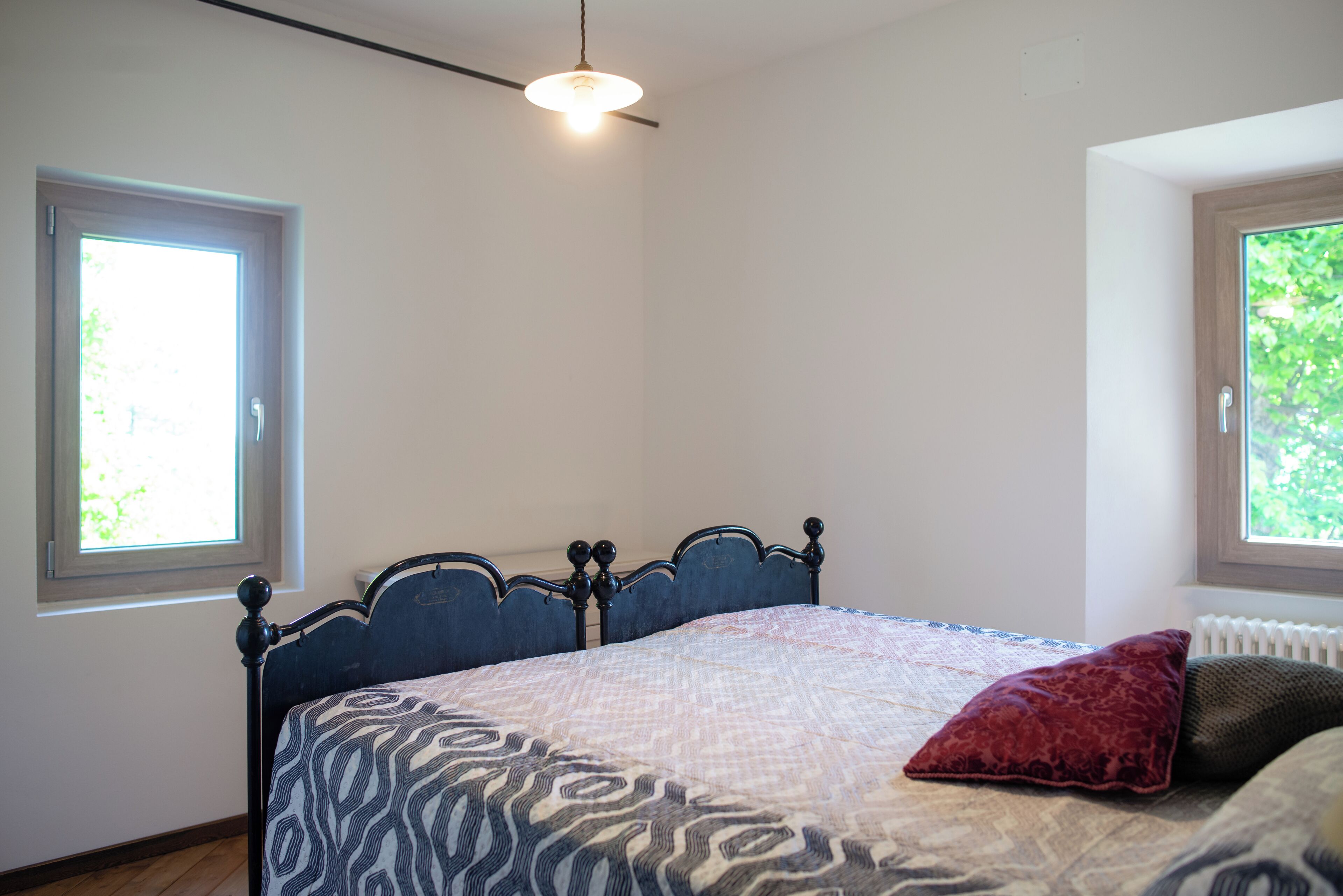 A bedroom with a bed, a window, and a radiator.