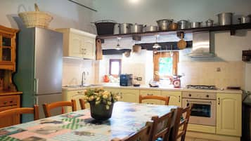 Une cuisine équipée d’une table à manger, de chaises, d’un réfrigérateur, d’un four, ainsi que de divers ustensiles et appareils de cuisine.