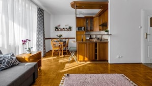 Um apartamento moderno com uma mesa de jantar de madeira, um sofá e uma cozinha com armários de madeira e micro-ondas.