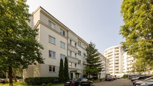Um edifício residencial com vários andares e uma área de estacionamento na frente.
