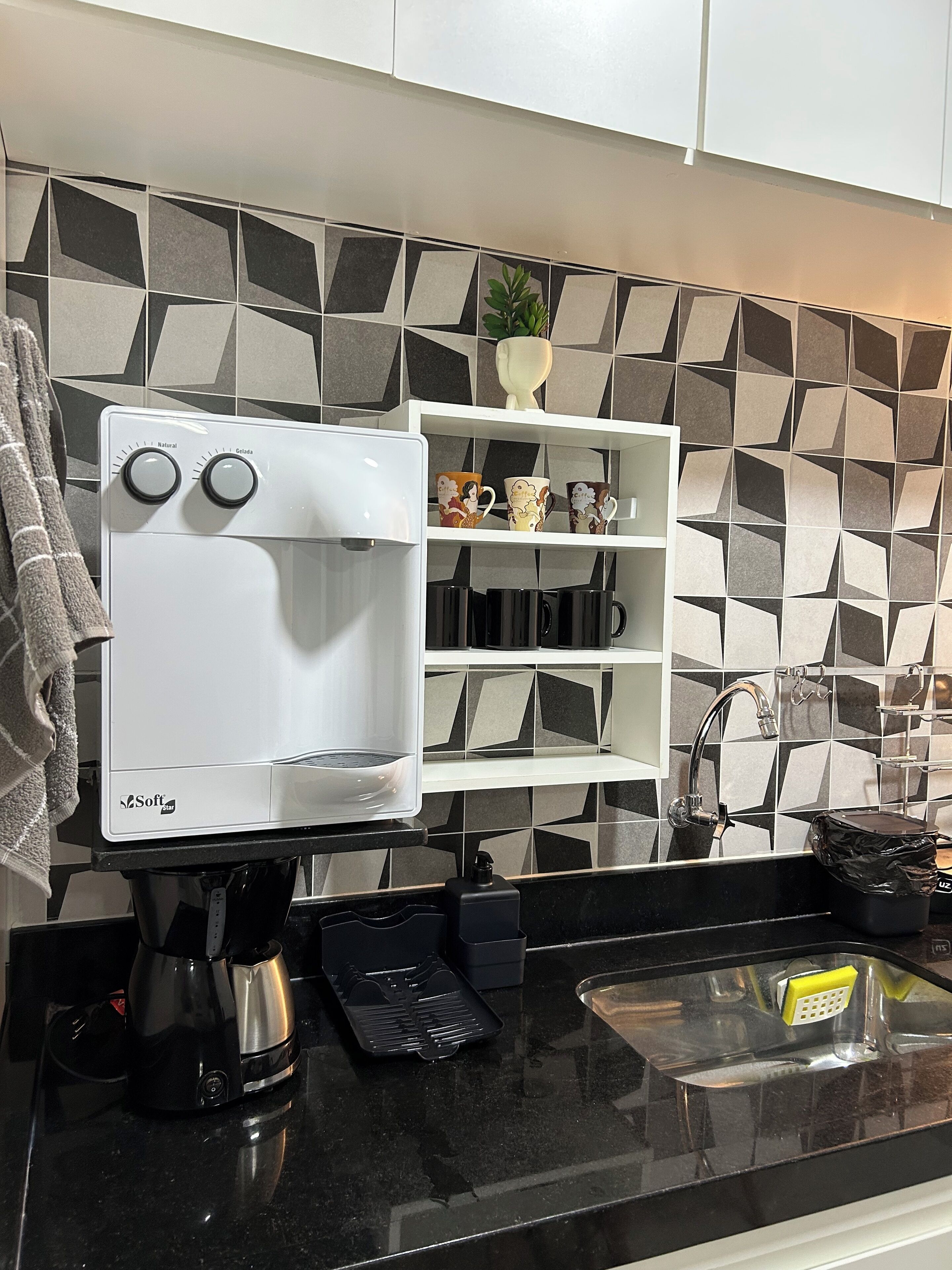 A modern kitchen with a coffee maker, a kettle, and a sink.
