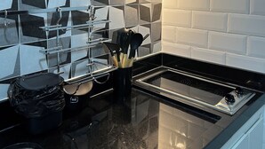 Una cocina moderna con salpicadero de azulejos blanco y negro, electrodomésticos de acero inoxidable y encimera negra.