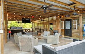 An outdoor patio with wicker furniture, ceiling fans, and a grill area. - Luxury Farm Stay with Hot Tub, Pool & Animals (Eutawville)