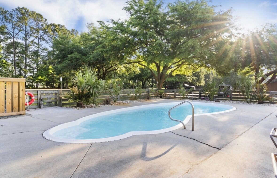 Ein Schwimmbecken mit Holzterrasse und Rettungsschwimmerstand.