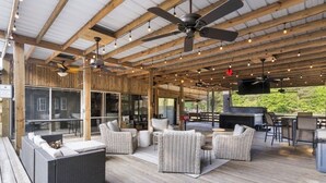 Una terrazza esterna con mobili in vimini, ventilatori a soffitto e un’area barbecue.