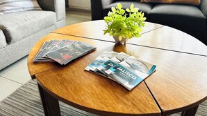 A round wooden coffee table with magazines and a small potted plant. - Espacio Libertad  (Guadalajara)