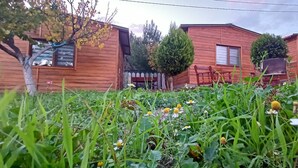 A row of wooden cabins with a grassy foreground and a wooden fence. - İda Tahtalıköy Bungalov (Edremit)