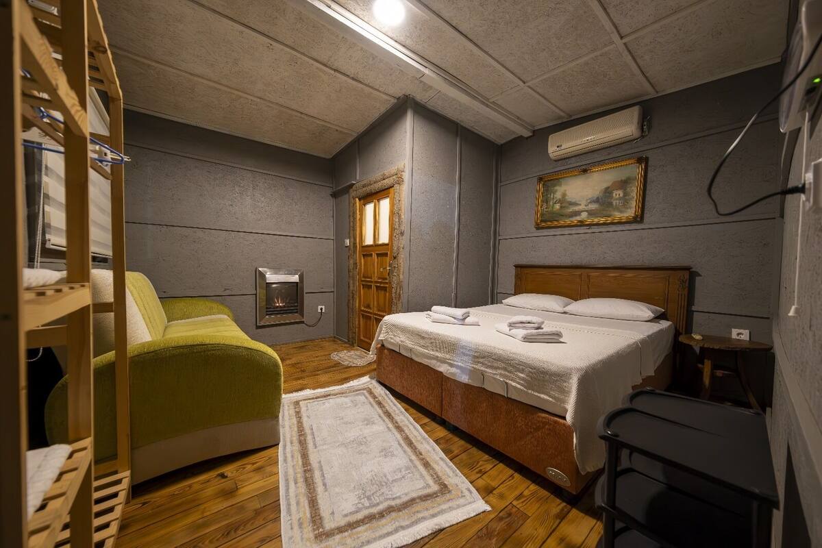 A bedroom with a bunk bed, a single bed, a fireplace, a painting, and a small table.