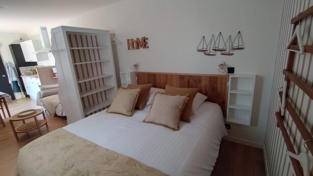 A bedroom with a bed, a wooden headboard, a wardrobe, and a shelf with a 'HOME' sign.