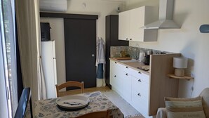 A compact kitchen with a dining area, featuring a table with a floral tablecloth, a fish plate, and a chair.