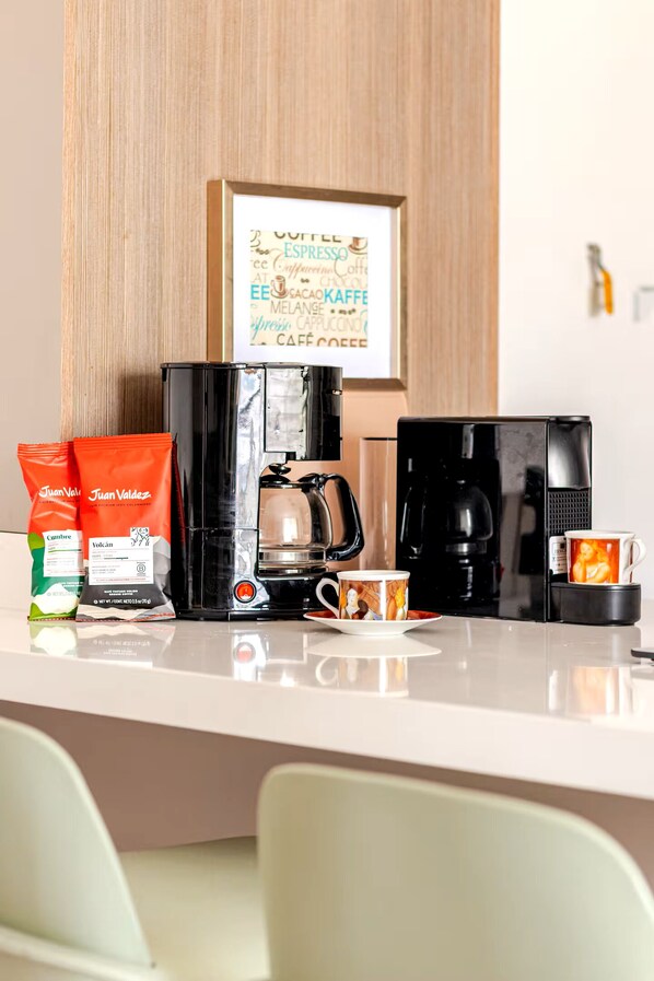 A coffee station with two espresso machines, coffee pods, and a mug on a counter.