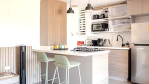 Une cuisine moderne dotée d’un îlot central, de tabourets de bar, d’un four à micro-ondes, d’une cuisinière et d’un réfrigérateur.