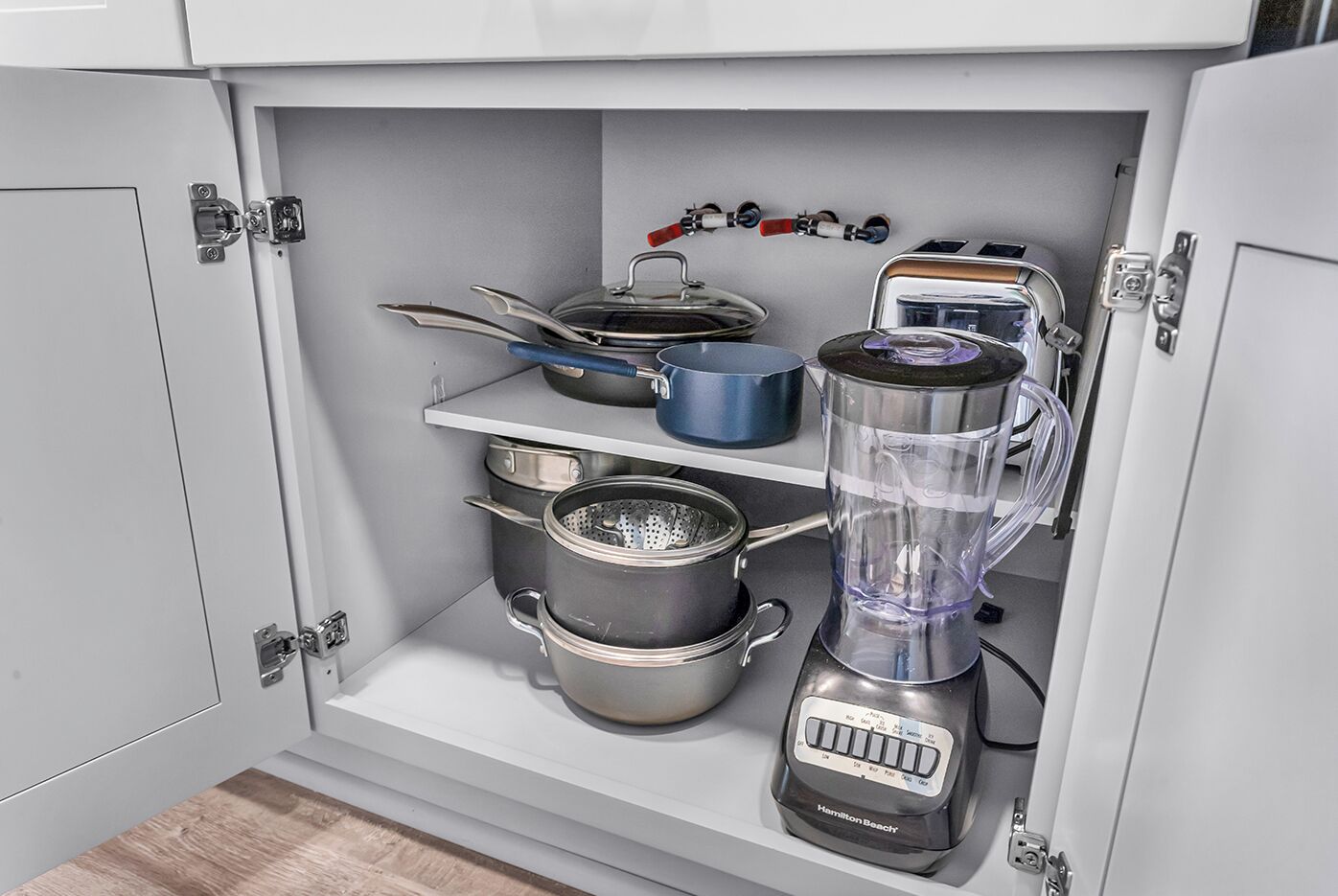 A kitchen with a built-in blender, a stove, and various pots and pans.