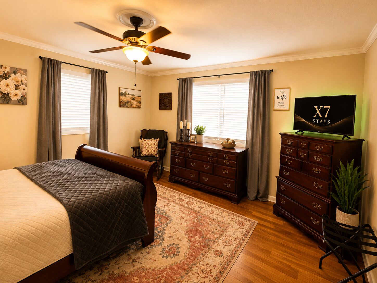 Une chambre à coucher comprenant un lit, une commode, un téléviseur et un ventilateur de plafond.