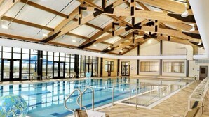 Piscina interior con techo alto y ventanas amplias.