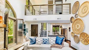 Un espacio habitable amplio con techo alto, una escalera y una cocina al fondo.