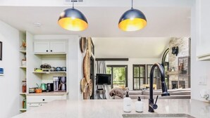 Cocina moderna con una isla central, dos lámparas colgantes, estufa integrada y un amplio ventanal con vistas al exterior.