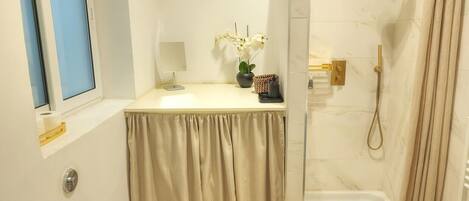 A bathroom with a toilet, a sink, a shower, and a window.