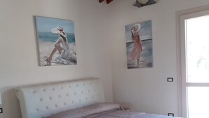 Ein Schlafzimmer mit einem weißen Bett, einem Nachttisch, einer Holzbalkendecke und zwei Bildern an der Wand.